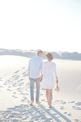 Rear view of a gentle sensual couple in love walking among the white desert