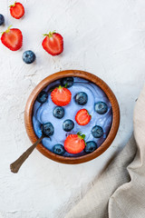 Blue matcha smoothies with berries and fruits in a bowl on a gray.