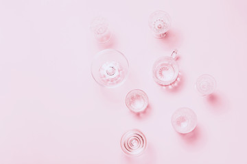 Many empty glasses on pink background. Top view, flat lay.