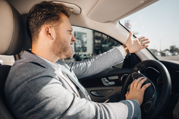 Angry driver in a traffic jam loosing his tamper and gesturing to let his car go.