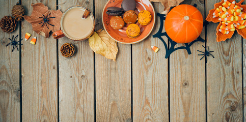 Halloween holiday background with coffee cup, pumpkin and autumn leaves on wooden table. Top view from above. Flat lay