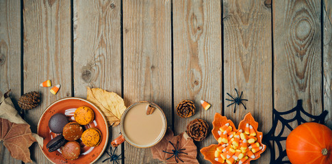 Halloween holiday background with coffee cup, pumpkin and autumn leaves on wooden table. Top view from above. Flat lay