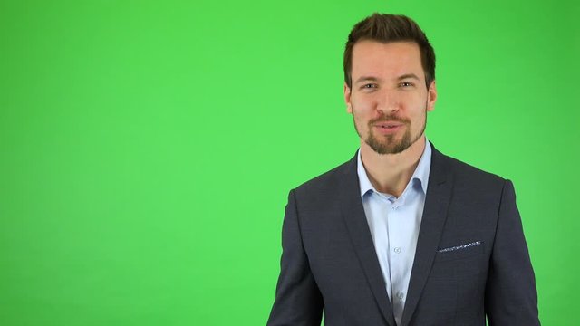 A young handsome businessman talks excitedly to the camera and points at it  - green screen studio