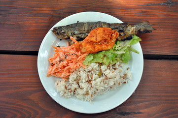 Trout fish and rice on a plate with herbs and carrots. horizontal top view