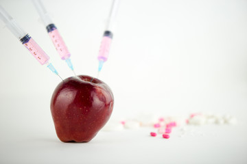 Concept: human GMO manipulation of nature and relative poisoned fruits. Close-up of an apple...