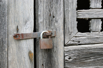 antique wooden window closed by an old rusty lock