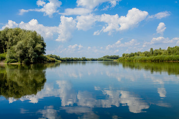 Obraz na płótnie Canvas Blue beautiful sky against the background of the river. Clouds are displayed in calm water. On the horizon, the green bank of the Dniester, place for fishing