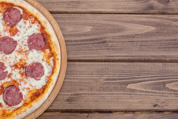 Italian Pepperoni pizza with salami on dark wooden background top view. Italian traditional food. Popular street food