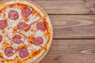 Italian Pepperoni pizza with salami on dark wooden background top view. Italian traditional food. Popular street food