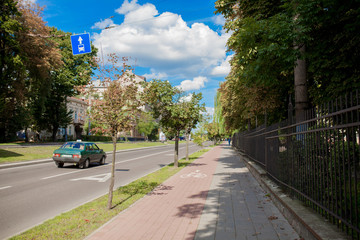 Fototapeta premium Protected bike lane between parking lane and sidewalk on city street. Bikers commuting on nice spring day.
