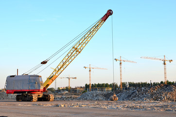 Fototapeta na wymiar Large crawler crane or dragline excavator with a heavy metal wrecking ball on a steel cable. Wrecking balls at construction sites. Dismantling and demolition of buildings and structures - Image