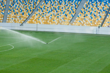 Automatic lawn grass watering system at the stadium. A football, soccer field in a small provincial...