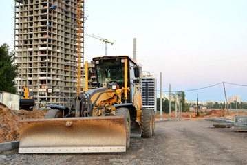 Сonstruction machine Motor Grader at a construction site level the ground and gravel stones for the construction of a new asphalt road. Road construction equipment
