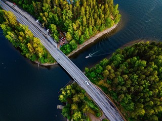 Aerial view of the bridge with a boat passing under it. Blue lake with summer houses in Finland.