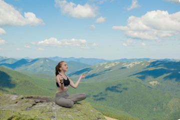Fototapeta na wymiar Girl doing yoga exercise lotus pose at the top of the mountain.