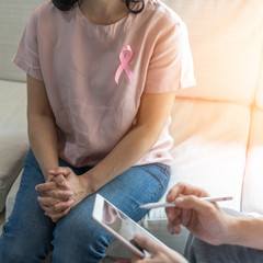 Fototapeta na wymiar Breast cancer pink awareness ribbon on woman patient consulting with doctor who diagnostic examining on obstetric - gynaecological female illness in medical clinic or hospital