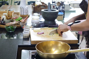 a lady cooking Thai food with brass wok 