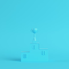 Pedestal with trophy cup on bright blue background in pastel colors. Minimalism concept