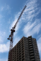 Russia, Novosibirsk, may 4, 2019: crane construction builds a tall brick building house against the blue sky