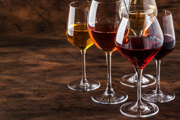 Wine set. Red, white and rose wine in assortment in wineglasses. Wine tasting, vintage wooden background, selective focus, copy space