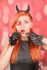 Fashion pretty young woman with red lollipop heart wearing black leather dress and devil horns