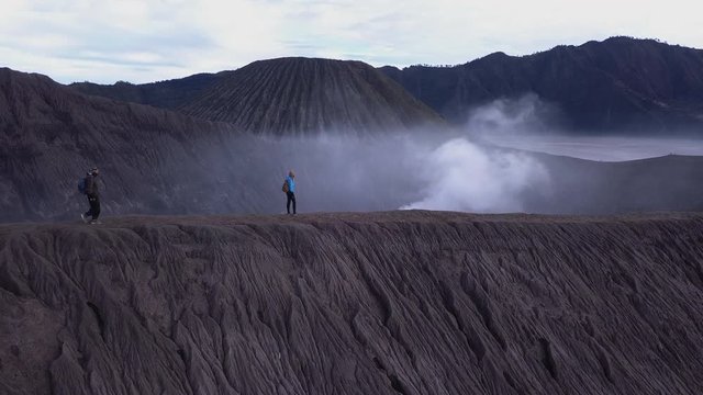 AERIAL: A hikers walks at the edge of Bromo volcano in Java island, Indonesia
