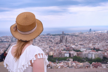 Fototapeta premium Tourist woman in hat looks at the panorama of Barcelona. Catalonia, Spain