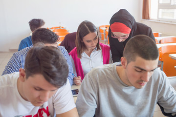 Female muslim professor explain lesson to students and interact with them in the classroom.Helping a students during class. University student being helped by female lecturer during class.