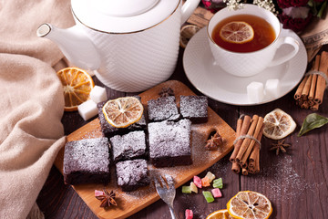 Pieces of chocolate cake with powdered sugar on the kitchen Board. Fresh homemade cakes. Chocolate biscuit. Brownie.