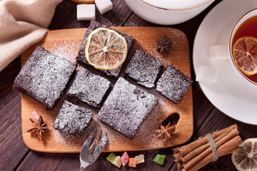 Pieces of chocolate cake with powdered sugar on the kitchen Board. Fresh homemade cakes. Chocolate biscuit. Brownie.