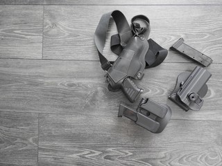 Gun with holster and clip on grey wooden background. The concept of cards