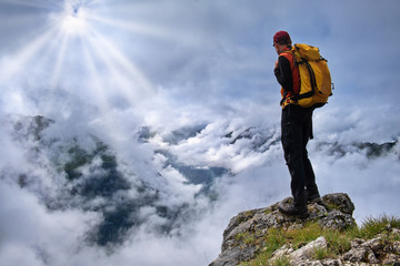 Mann bei Wanderung steht am Gipfel mit Aussicht auf Wolkenmeer