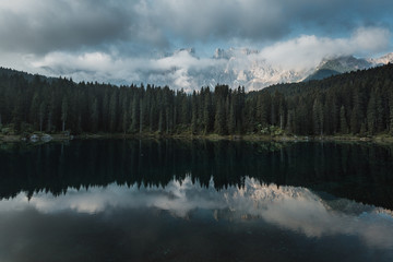 Scenic image of Fairytale lake during sunrise. Amazing nature landscape with azure mountain lake Carezza or Karersee. Awesome alpine highlands in sunny day. Dolomites mountains. Italy