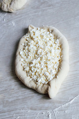 Homemade Ajarian Khachapuri with Suluguni Cheese. Stage of work. Preparation for baking. Raw Suluguni before baking