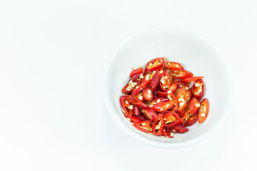 Chopped and slices of red chilli in a white cup isolated on white background,top view