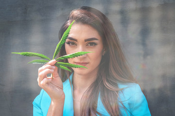 The girl holds a hemp leaf in her hand and smiles. Conceptual photo