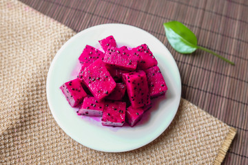 A plate of seductive red dragon fruit placed on a tablecloth top view