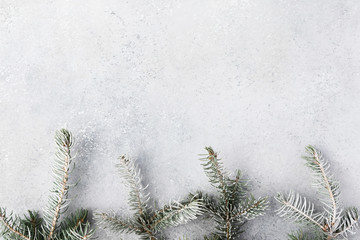 Christmas background with a gifts, fir tree branches, cones and snow on gray concrete table. Christmas composition. Flat lay. Top view