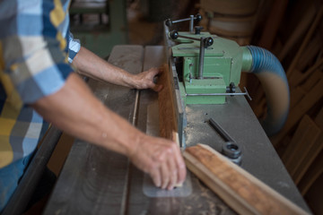 a carpenter processes a massive piece of wood