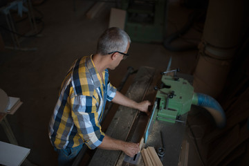 a carpenter processes a massive piece of wood