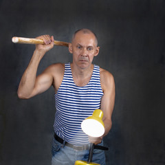 A man with a stick in one hand and a luminous yellow table lamp in the other hand.