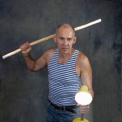 A man with a stick in one hand and a luminous yellow table lamp in the other hand.