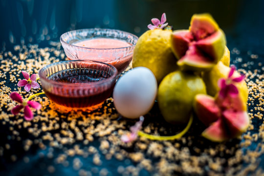 Treatment of dry skin with the help of face mask on a wooden surface consisting of honey, guava pulp, egg yolk, and some oatmeal, well mixed in a glass bowl along with raw ingredients.