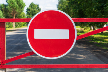 The sign "no entry" on the background of the city road and trees in the summer.