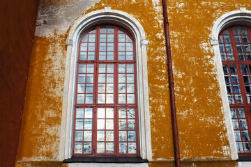 Large windows in the shabby wall of the old historical church.