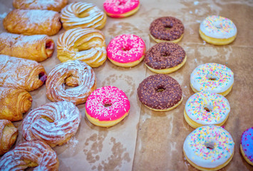 Assorted pastry – sweet donuts with colorful – pink, chocolate and white -  glaze and sprinkles