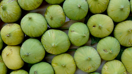 Closeup of unripe green figs in wooden crate