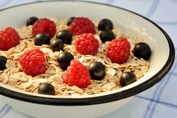 Oatmeal with raspberry and black currant on the table close-up
