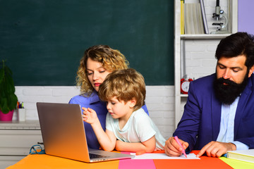 September 1. School family. Education. Kids at preschool. Boy from elementary school with parents in classroom. School kids. First day at school. Home schooling. Cute pupil and his parents. Parenting.