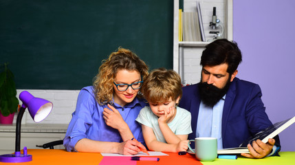 Parenting education. Boy from elementary school. Educational process. Supporting pupils at school. School, learning and education concept. Happy family. Mother, father and son together schooling.